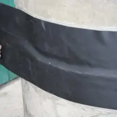 Arbeiter dichtet mit schwarzer Folie eine Zisterne ab.