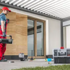 Handwerker mit Werkzeugkasten bereitet sich vor, das Vordach Wandanschluss abzudichten.