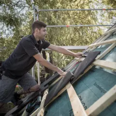 Handwerker verlegt Dachziegel, um die Dachkehle abzudichten.