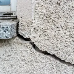 Ein großer Riss im Putz neben einem Fensterbrett. Die Rissverpressung Kosten sind hier ein wichtiges Thema für Hausbesitzer.
