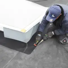 Dachdecker dichtet mit Heißluftgerät die Attika auf einem Flachdach ab.