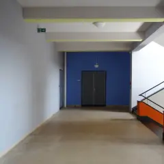 Ein Flur mit hellem Estrich, blauer Wand und auffälliger Treppe. Der Boden ist nach DIN-Norm verlegt.