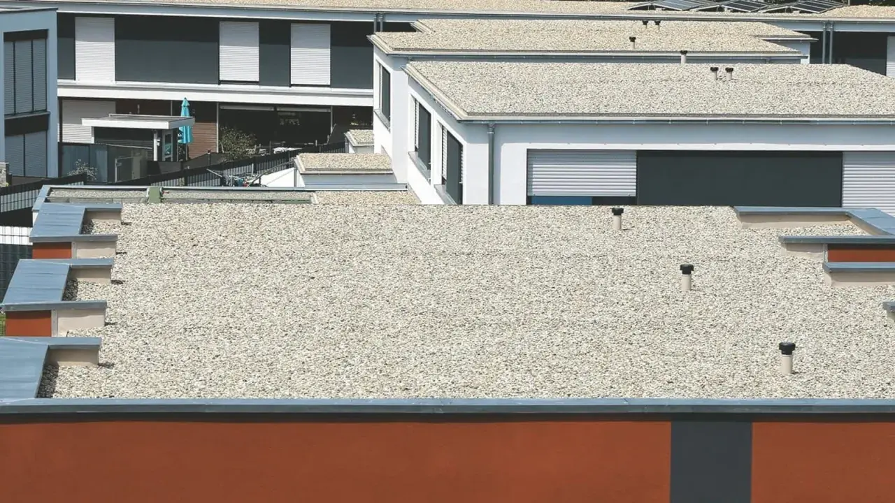 Mehrere moderne Gebäude mit verschiedenen **Flachdach Arten**, bedeckt mit Kies und mit sichtbaren Entlüftungsrohren.