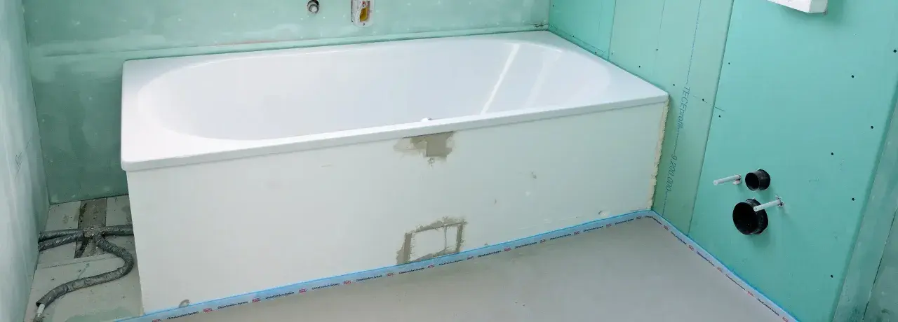Badewanne in einem Rohbau. Die Anschlussfugen abdichten ist der nächste Schritt, bevor die Fliesen verlegt werden.
