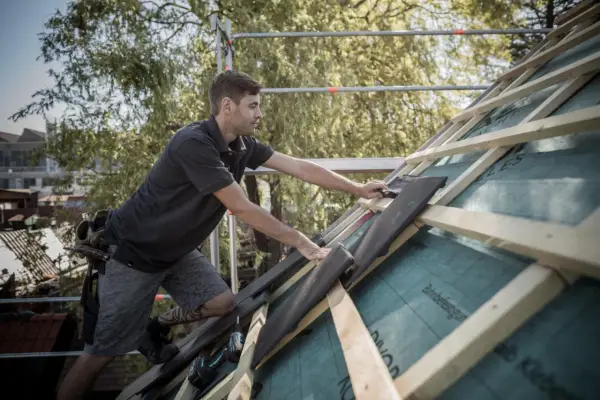Handwerker verlegt Dachziegel, um die Dachkehle abzudichten.